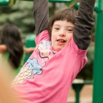 child goes over monkey bars at inclusive playground